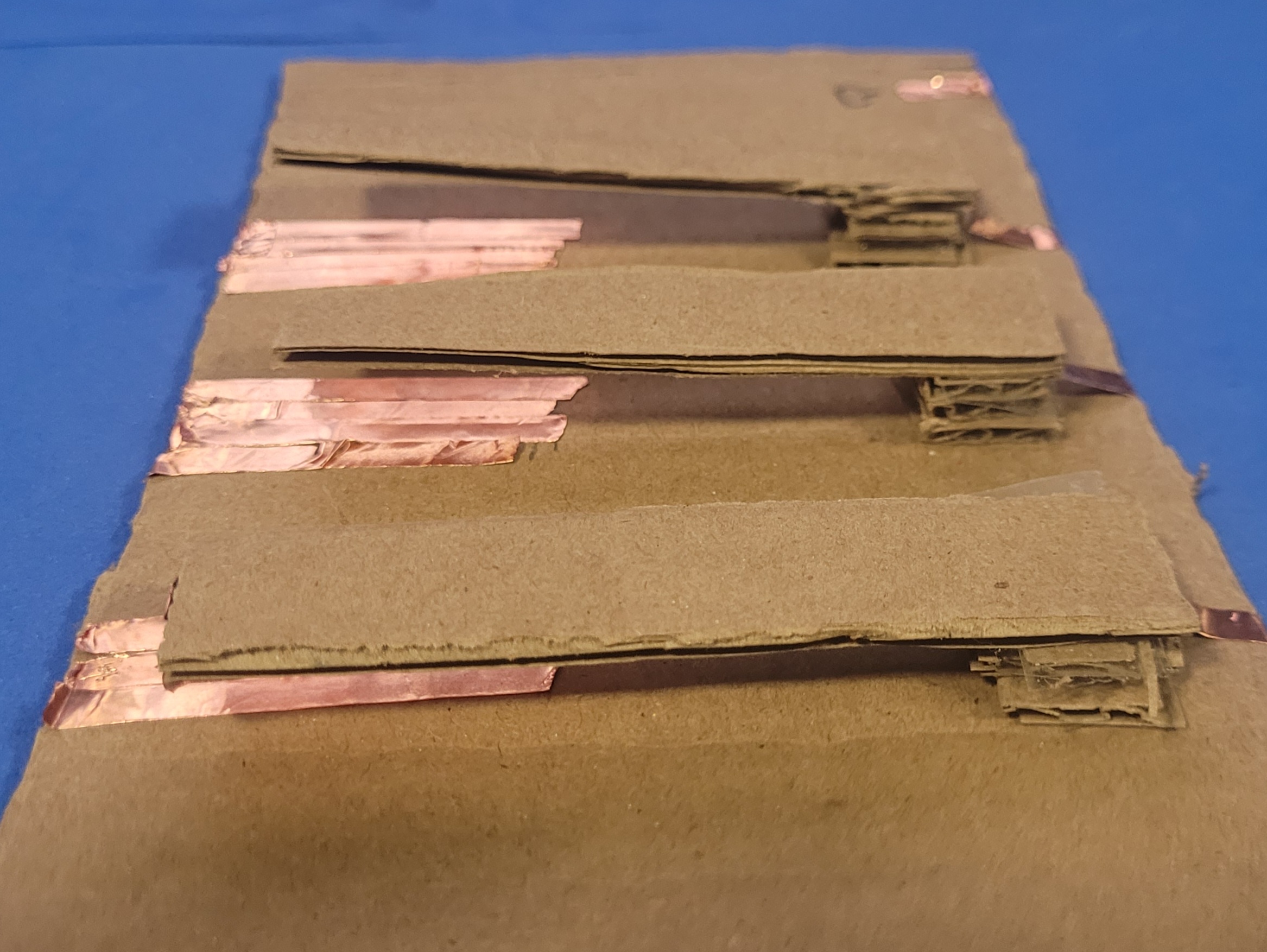 A photo showcasing the unattached created cardboard circuit emulating that of a piano. the keys will connect the ground and key when pressed.