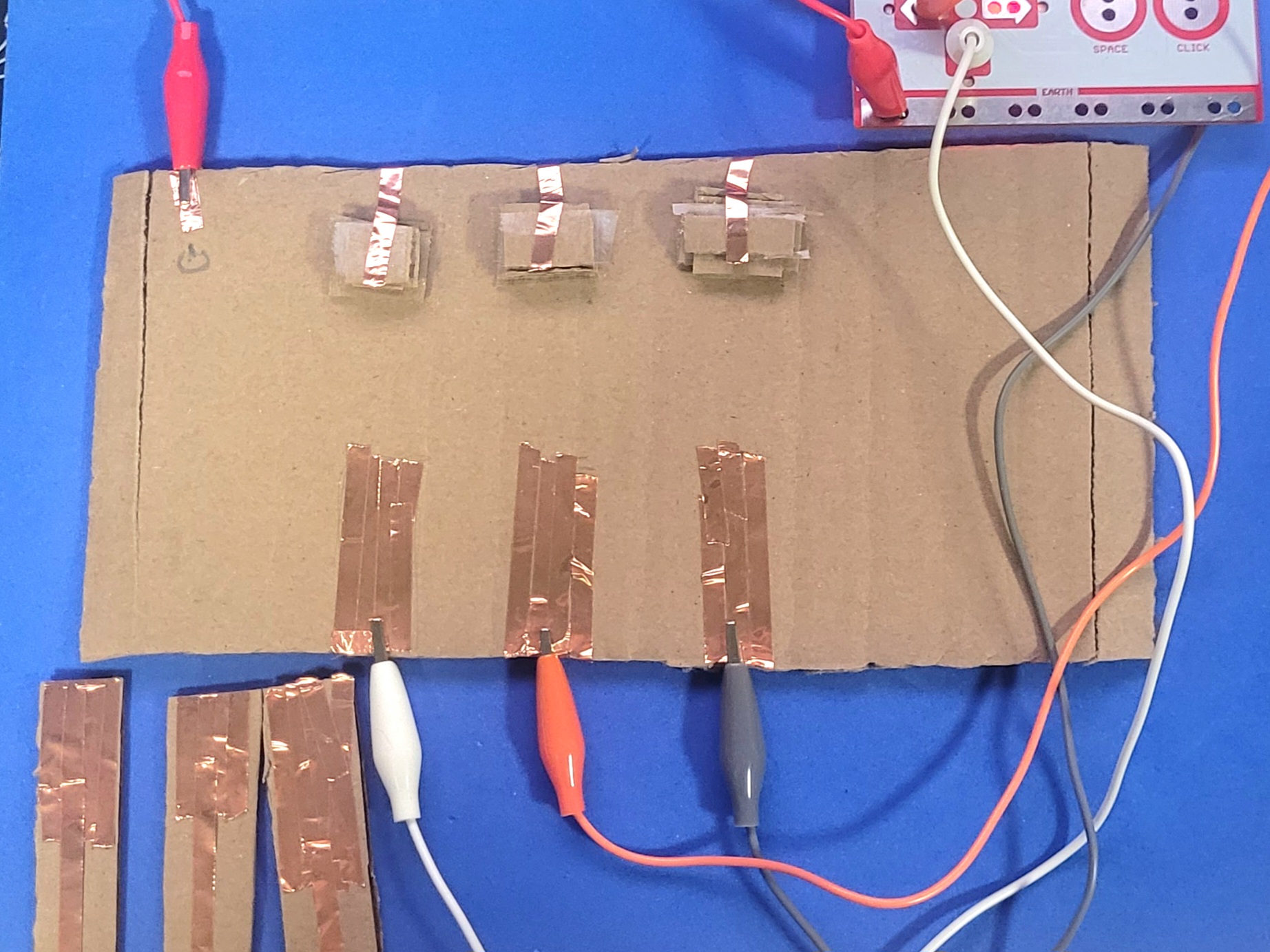 A photo showcasing the unattached created cardboard circuit emulating that of a piano. the keys will connect the ground and key when pressed.