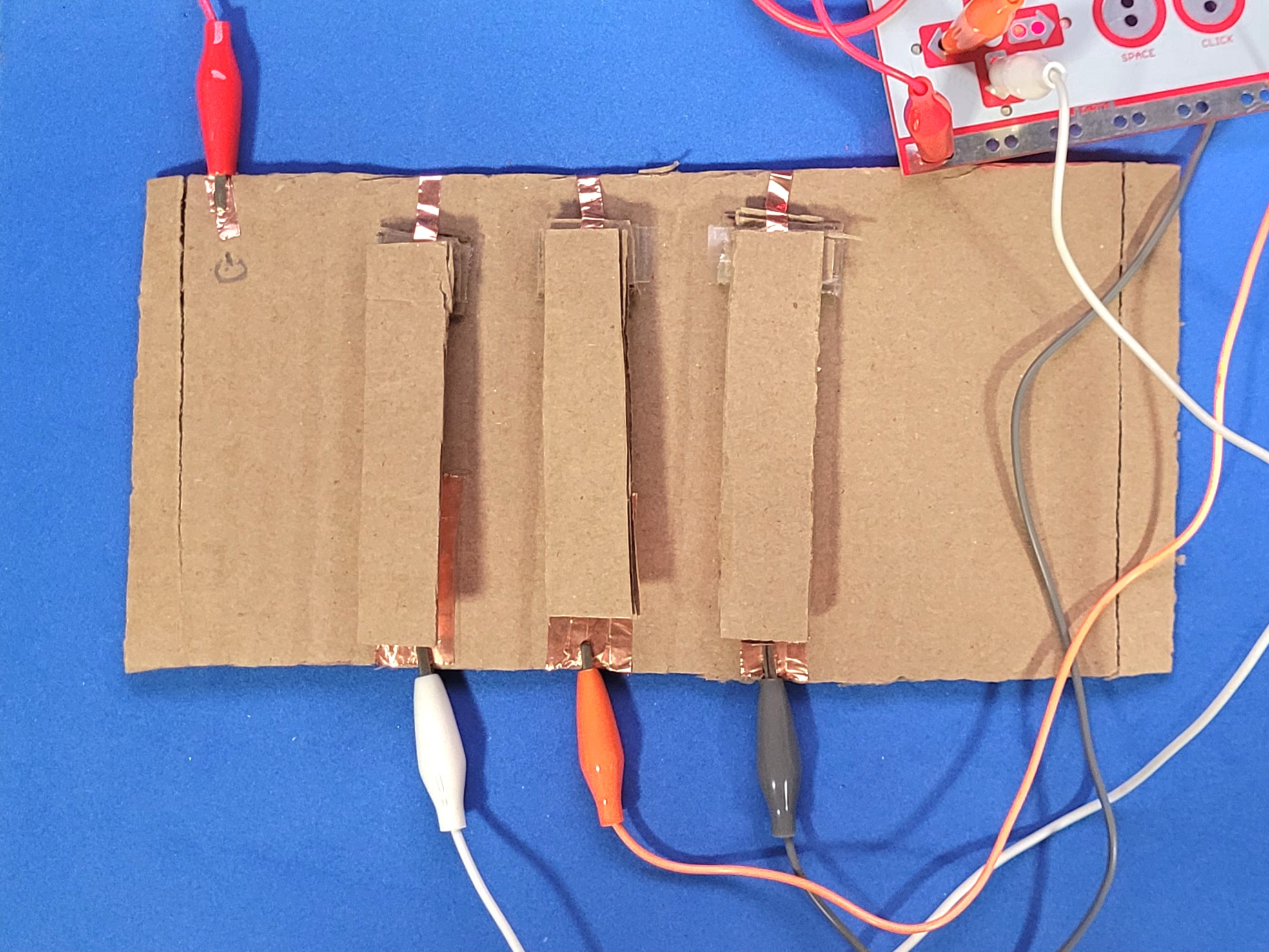 A photo showcasing the created cardboard circuit emulating that of a piano. the keys will connect the ground and key when pressed.