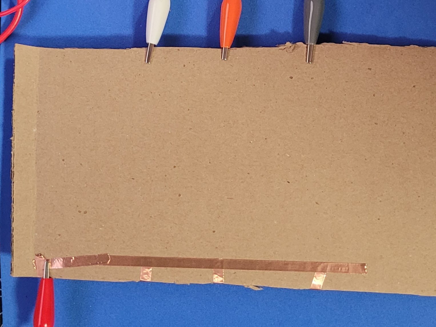 A photo showcasing the bottom of the circuit, showing the connects to to the MakeyMakey using copper tape