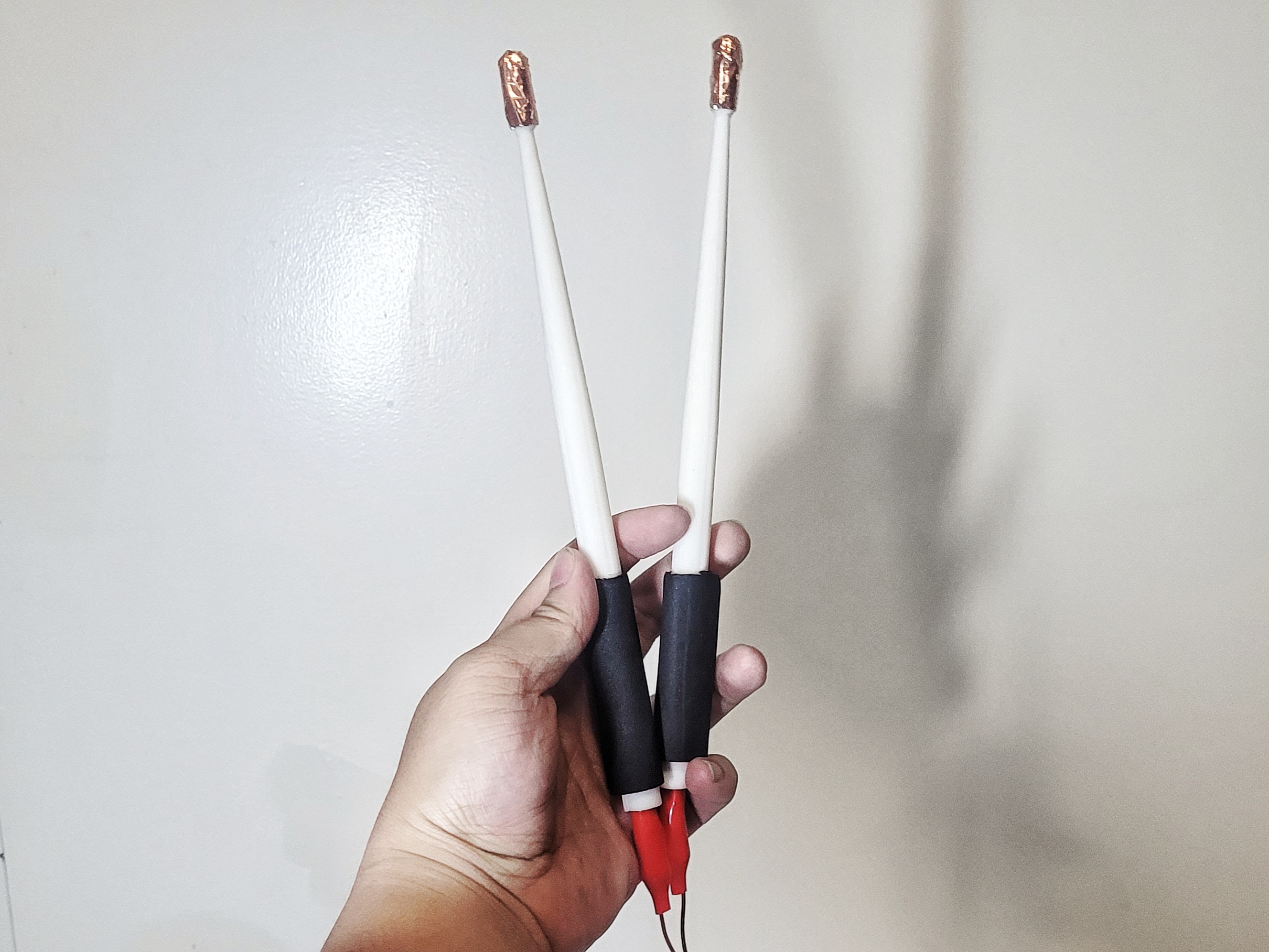 The modified 3D printed drumsticks that has wire running inside of it to the tip that is covered in copper tape.